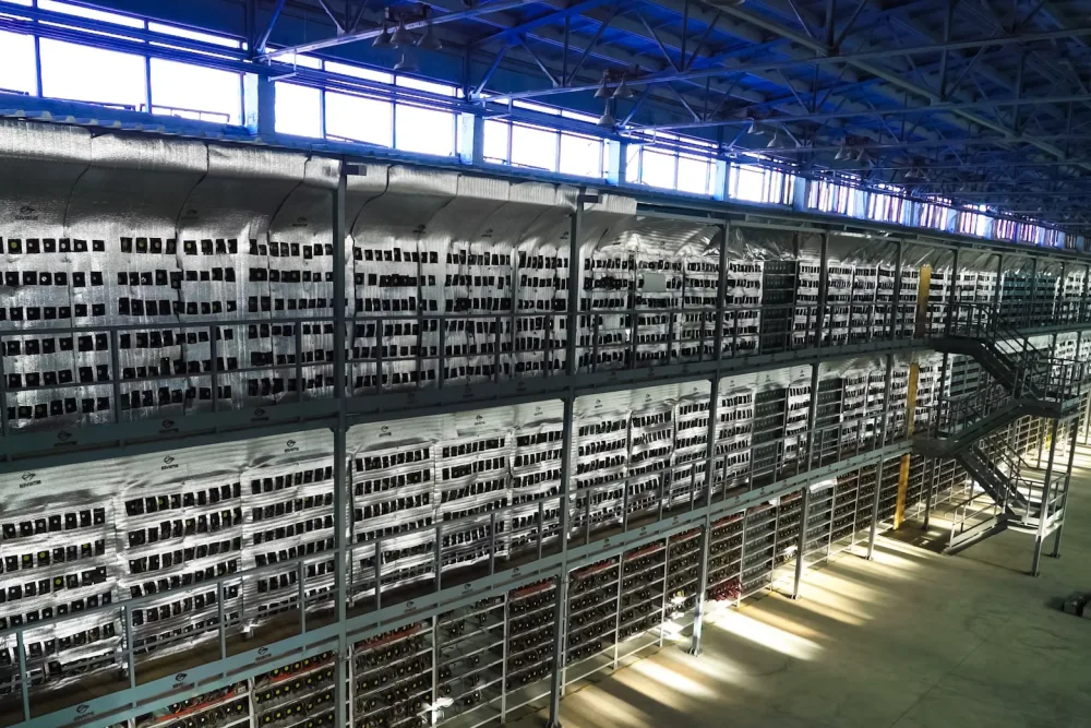 Warehouse-scale bitcoin mining farm with racks of ASIC miners stacked several storeys high